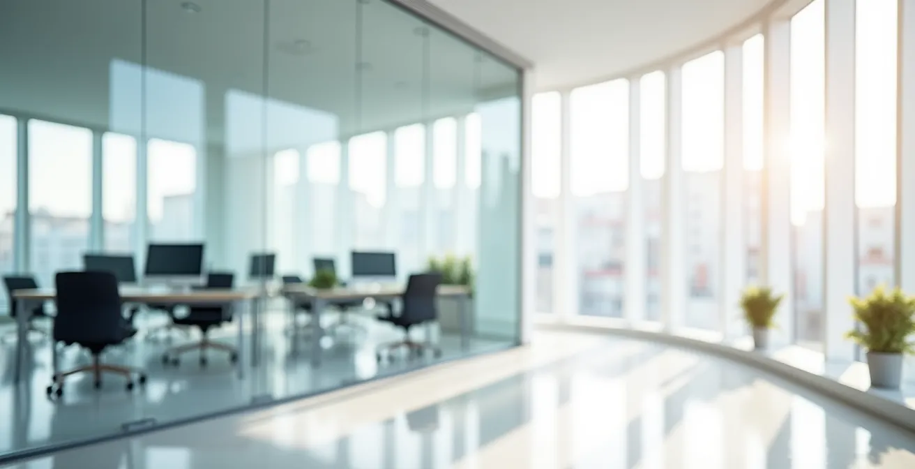 Vue environnementale d'un espace de travail moderne avec architecture épurée et équipements informatiques flous en arrière-plan